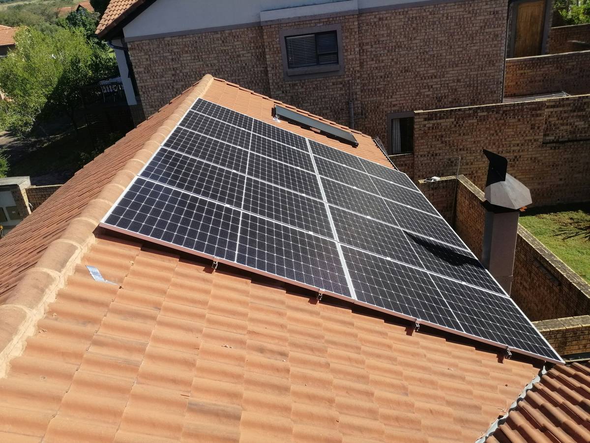 Close-up of monocrystalline solar panels efficiency on a residential roof with clear sky, showing uniform dark cells and minimal frame reflection